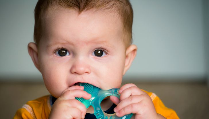 baby with teething ring in mouth